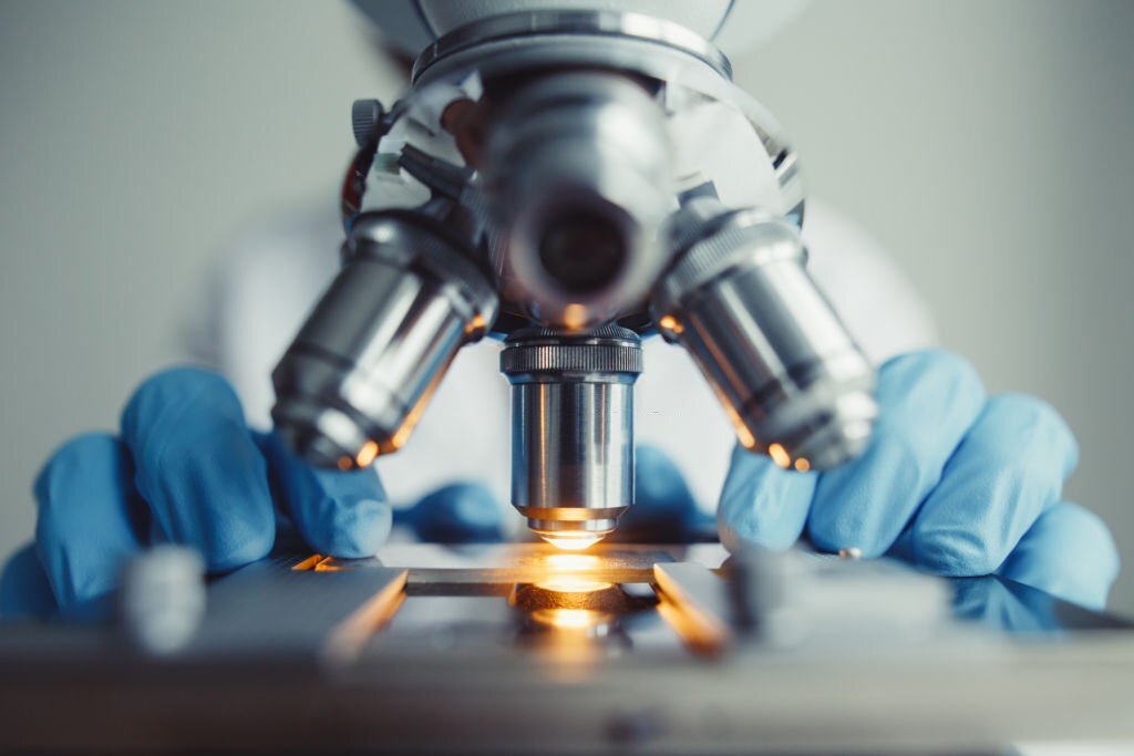 Close up of examining of test sample under the microscope in laboratory.